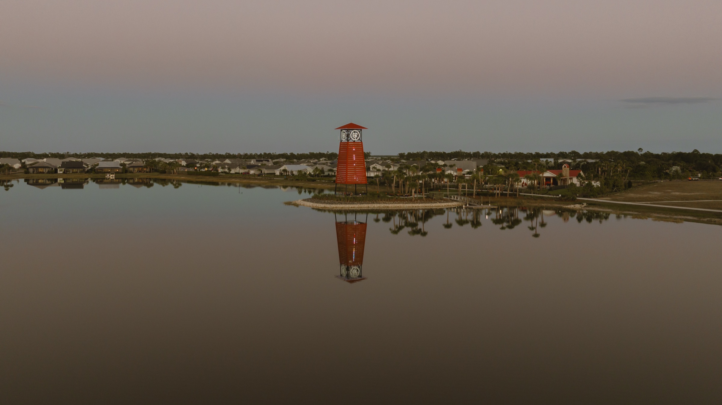 Babcock Ranch clock tower and surrounding homes reflected in the lake at dusk